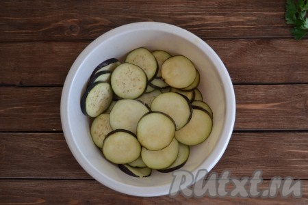 Нарезать вымытые баклажаны кружочками толщиной, примерно, 3-4 мм. Обильно посолить, перемешать и оставить на 20 минут, чтобы ушла горечь. Затем смыть соль и обсушить баклажаны на полотенце.
