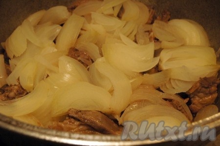 Через 30 минут открыть казан и поверх мяса выложить нарезанный лук. Не перемешивать. Закрыть крышкой и продолжать готовить бараньи рёбрышки, не открывая крышку, минут 45.