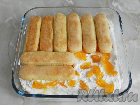 Выложить на мандарины еще слой из печенья савоярди, смоченного в сиропе, и оставшийся крем. Накрыть форму с десертом пищевой плёнкой и убрать на ночь в холодильник.
