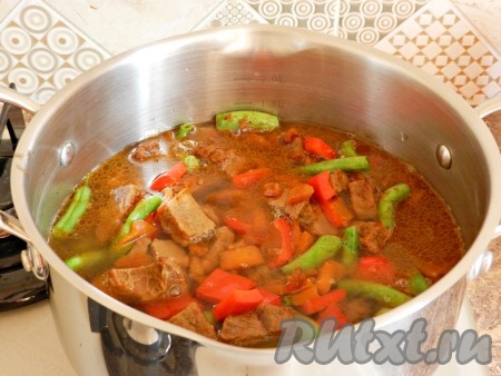 Переложить в кастрюлю, влить горячую воду, чтобы она покрывала мясо с овощами примерно на 2 см.
