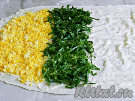 Лаваш разделить визуально на 4 примерно равные полоски. Первой полоской выложить натертые яйца, рядом разложить нарезанные листья салата.
