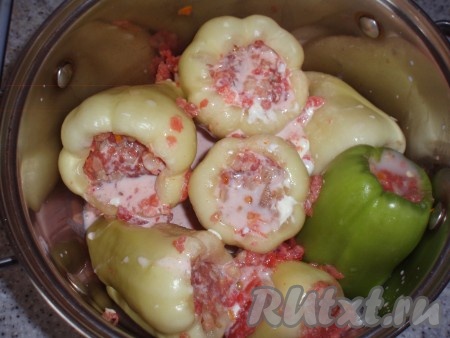 Залить соусом перцы, фаршированные мясом и перловкой, и поставить на огонь. Когда соус закипит, уменьшить огонь и тушить около 40 минут.
