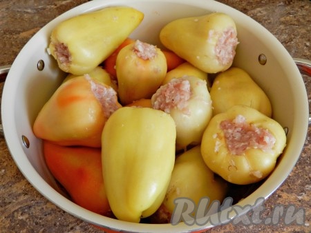 На дно кастрюли выложить половину заправки. Перец начинить фаршем и уложить плотно в кастрюлю.