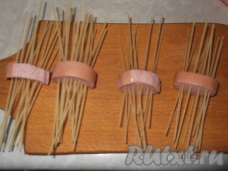 В наши сардельки, заранее нарезанные, вставляем по кругу спагетти.
