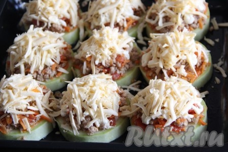 Выложить сыр поверх начинки. На дно противня налить немного воды и поставить противень в разогретую духовку. Запекать кабачки с фаршем и сыром при температуре 200 градусов, без верхнего нагрева, примерно 25-30 минут. 