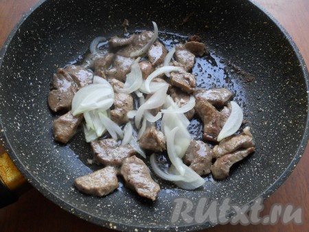 Обжаривать мясо, перемешивая, на довольно сильном огне около 5 минут. Репчатый лук очистить, разрезать пополам. Половину луковицы нарезать тонкими полукольцами и добавить к мясу. Обжаривать все до мягкости лука. Мясо остудить.
