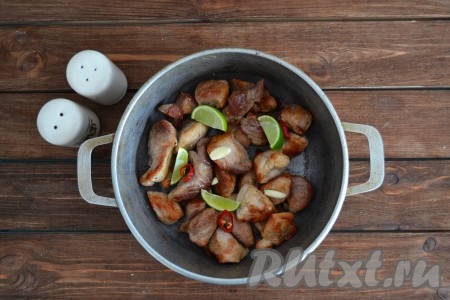 Острый перец нарезать колечками, чеснок - пластиками, лайм - небольшими дольками и выложить в казан со свининой. Остроту блюда регулируйте под свой вкус. 
