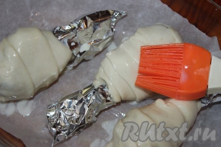 Противень для запекания застелить пергаментной бумагой, выложить подготовленные куриные голени на пергамент. Для того чтобы тесто приобрело румяную корочку, необходимо смазать его яичным желтком, взбитым с&nbsp; помощью вилки. По желанию посыпать кунжутом. Далее поставить противень в разогретую до 180 градусов духовку и выпекать примерно 35-40 минут до появления устойчивой золотистой корочки.
