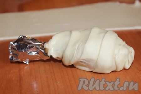 Каждую голень обмотать полосками слоеного теста по спирали, слегка отступая от кости, делая небольшой нахлест теста друг на друга. Для того чтобы не подгорели концы голеней, их необходимо завернуть в фольгу.
