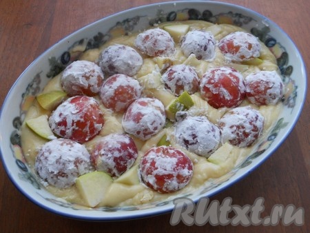 Сверху яблок разложить сливы разрезом вниз, вдавливая сливы пальцами в тесто.