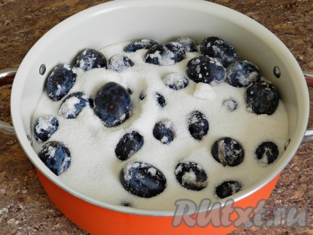 Сливы выложить в посуду для варки, всыпать половину сахара.
