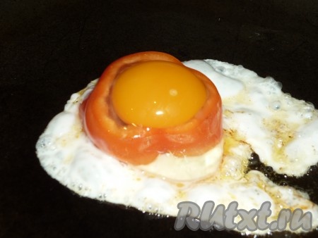 Вбить яйцо в кружочек болгарского перца. Я готовила одну порцию завтрака, поэтому жарила одну яичницу в перце. Но на сковороде можно сделать одновременно и несколько порций, вбивая по яйцу в каждый кружочек перца. Помидора и перца хватит на несколько порций. Посолить и поперчить по вкусу, огонь уменьшить до среднего и готовить блюдо под закрытой крышкой.
