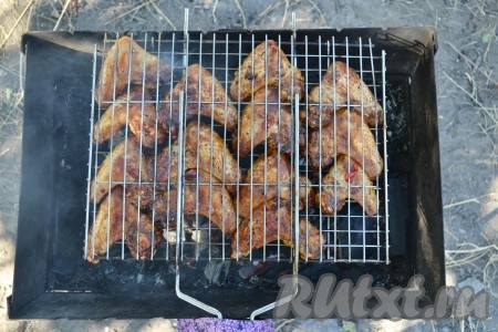 Замаринованные куриные крылья выложить на решетку на одинаковом расстоянии друг от друга (можно жарить и на шампурах, но только каждое крылышко необходимо нанизывать на два шампура одновременно), готовить на мангале на разогретых углях. Переворачивать решетку нужно каждые 2-3 минуты, чтобы мясо равномерно прожарилось. Время приготовления зависит от жара углей, мы приготовили за 10-15 минут. 