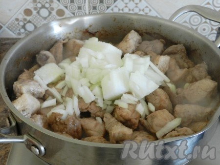 Затем в сковороду с мясом добавить нарезанный кубиками лук, перемешать. Обжаривать лук со свининой в течение 5-7 минут, периодически перемешивая.
