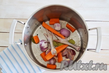 В большую кастрюлю выложить лавровые листья, чёрный перец горошком, тмин, розмарин, гвоздику, очищенный лук, очищенную и разрезанную на 2-4 части морковь, лапки и потроха петуха.
