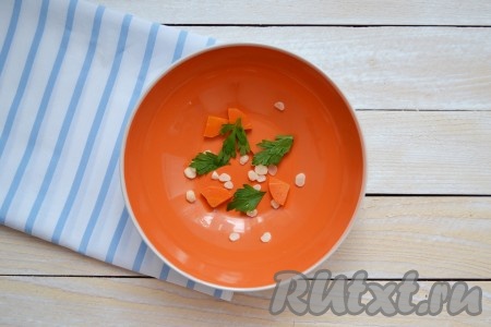 В миски разложить мелко нарезанные зубчики чеснока, кусочки моркови, которая варилась в бульоне, и по несколько веточек петрушки.
