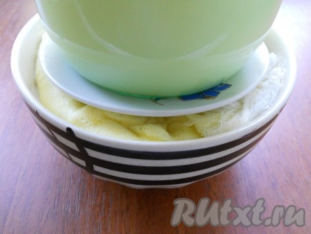 Сверху поместить блюдце меньшего размера, чем объем посуды с творогом, и поместить гнет (банку с водой, например).
