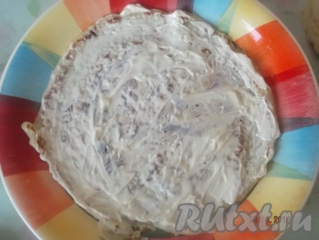 В отдельной мисочке смешиваем майонез и пропущенный через пресс чеснок. Когда коржи остынут, можно приступать к формированию тортика. На поднос или блюдо с ровным дном выкладываем первый корж, смазываем его смесью майонеза и чеснока.