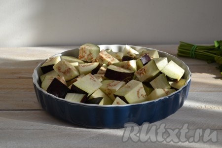 Баклажаны вымыть и нарезать крупными кусочками. Обильно посолить и оставить на 10-15 минут, а затем слить образовавшуюся жидкость, соль смыть. Баклажаны выложить в форму для запекания (при желании форму можно смазать растительным маслом). 
