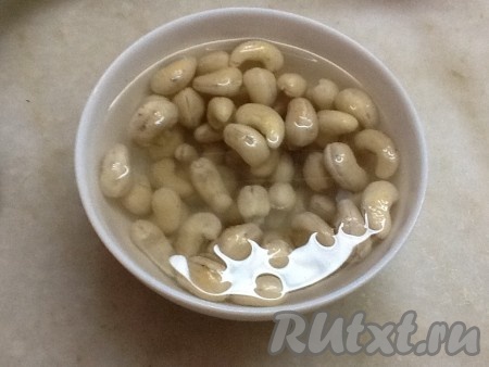 Берем орешки кешью, замоченные в горячей воде, воду сливаем, обсушиваем их и складываем в блендер. Измельчаем орехи до небольших кусочков. 