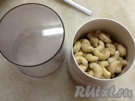 Берем орешки кешью, замоченные в горячей воде, воду сливаем, обсушиваем их и складываем в блендер. Измельчаем орехи до небольших кусочков. 