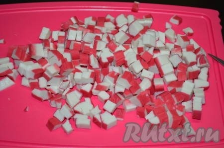 Яйца сварить в течение 10 минут с момента закипания воды, затем полностью остудить их и очистить. Крабовые палочки нарезать кубиками.