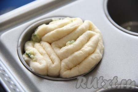 Формочки для выпечки кексов слегка смазать растительным маслом. Затем выложить в лунки формы по две или три заготовки. Оставить&nbsp;заготовки булочек с чесноком и зеленью, прикрыв полотенцем, на 20-30 минут. 