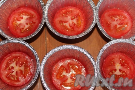Формочки для запекания слегка смазать растительным маслом. На дно формы выложить по одному кружочку помидора.
