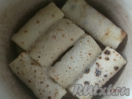 В кастрюлю или форму для запекания (при желании, дно можно смазать растительным маслом) выкладываем слоями: первый ряд блинов с начинкой, посыпаем сахаром. 
