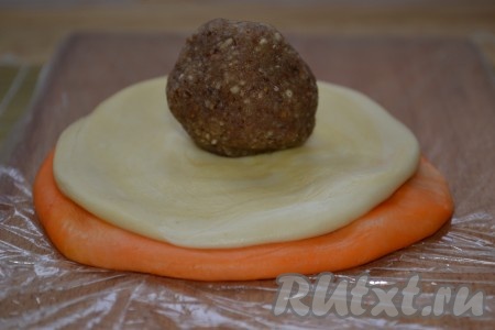 Каждый рулет ставим, как "столбик", и раскатываем в лепешку круглой формы. У нас получится 6 белых и 6 оранжевых лепешек. Оранжевые раскатываем чуть больше диаметром, чем белые. Выкладываем сначала оранжевую лепёшку, на неё кладём белую лепёшку. Из начинки скатываем шарики и выкладываем в центр лепёшек.

