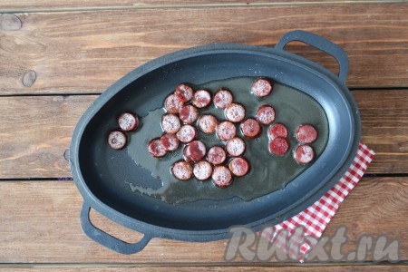 На сковороде на среднем огне разогреть подсолнечное масло, выложить колбасу и обжарить с двух сторон, чтобы она прогрелась (это займёт примерно 2 минуты). А если куски колбасы побольше, то прогрейте на сковороде чуть подольше.
