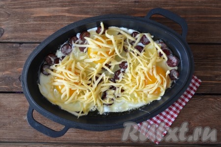 Яичницу с колбасой посыпать сыром и жарить на среднем огне до тех пор, пока полностью не "схватится" белок.&nbsp;
