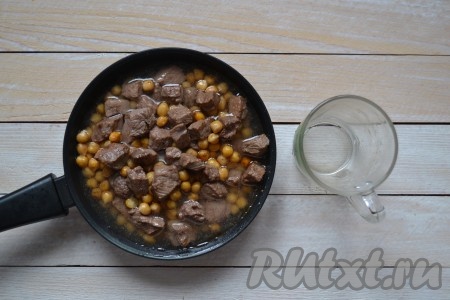 Влить в сковороду воду (она должна полностью покрыть содержимое сковороды), накрыть крышкой и тушить говядину с нутом на слабом огне в течение 1 часа. Жидкость должна слабо кипеть, а не бурлить.
