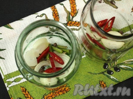 Банки хорошо вымыть, стерилизовать не нужно. На дно литровых банок распределить поровну лук и острый перец, добавить в каждую баночку по 3-4 кусочка стебля хрена, лавровому листочку, 5 горошин чёрного перца и 3 горошины душистого.
