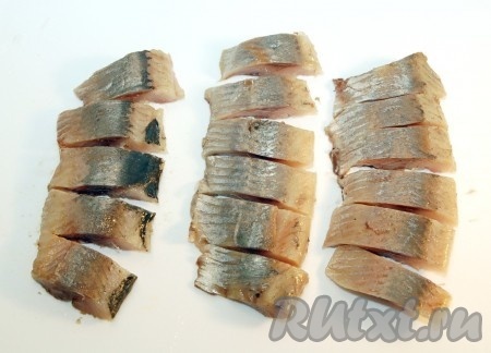 Разделать солёную сельдь на филе, тщательно удаляя косточки. Филе нарезать на кусочки.
