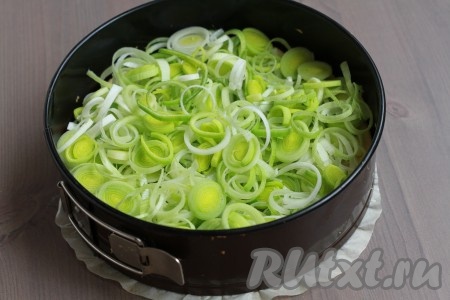 На полуготовое тесто выложить нарезанный кольцами лук порей.
