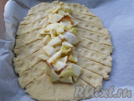 Также яблоки посыпать сверху 2 столовыми ложками сахара. С двух сторон теста сделать разрезы, начиная от яблок и заканчивая краями.