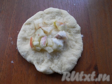 Дрожжевое тесто обмять и разделить на 20 частей. Каждую часть теста расплющить в лепёшку, в середину поместить по 1-2 чайных ложки яблок, посыпать 0,5-1 чайной ложкой сахара.