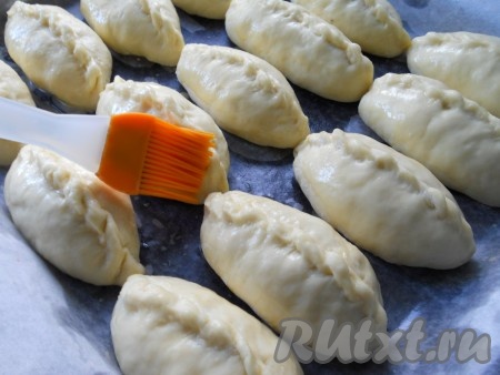 Желток соединить с молоком. Оставить пирожки, прикрыв полотенцем, в тёплом месте на 30 минут, после чего смазать каждый пирожок смесью желтка и молока.