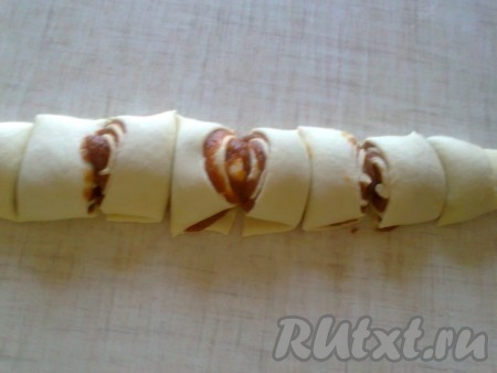 Получившийся рулет нарезаем на части и выкладываем на противень, смазанный растительным маслом или застеленный пекарской бумагой. Можно не разрезать рулет на части, а выпекать целиком, а уже готовый рулет нарезать на части.