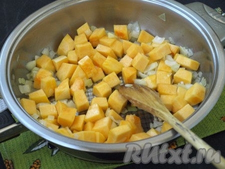 В сковороде разогреть подсолнечное масло, выложить мелко нарезанный лук и обжарить, иногда помешивая, до прозрачности. Добавить в сковороду тыкву, убавить огонь и готовить под крышкой 15 минут, периодически перемешивая.