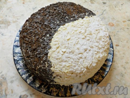 Одну половину торта "День и ночь" обсыпать натертым черным шоколадом, вторую половину - белым. У меня был шоколад в виде мелких осколков. Немного присыпать темную сторону торта какао-порошком, а белую - сахарной пудрой.
