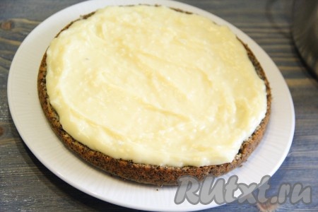 Приступаем к сбору маково-кокосового торта, для этого на плоскую тарелку или подставку нужно выложить первый корж и хорошо смазать его кремом.