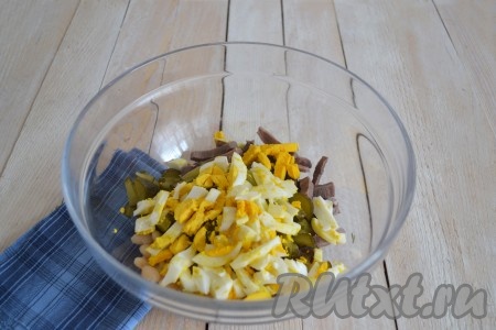 Отварить куриные яйца вкрутую и нарезать соломкой или как вам будет удобно. Выложить в миску с салатом.
