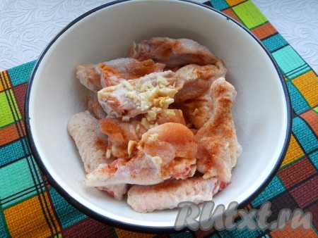 Посыпать крылья специями для курицы, посолить немного, выдавить через чесночницу или мелко нарезать чеснок, перемешать.

