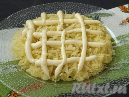 Заранее отварить морковь и картошку в кожуре до готовности (на отваривание моркови потребуется минут 30-35 с момента закипания воды, картошки - минут 25, готовые овощи будут легко прокалываться ножом), затем полностью остудить. Яйца отварить в течение 10 минут после закипания воды, остудить их. Очищенный картофель натереть на крупной тёрке и выложить на плоскую тарелку в форме круга. Картофель можно немного посолить и смазать майонезом.