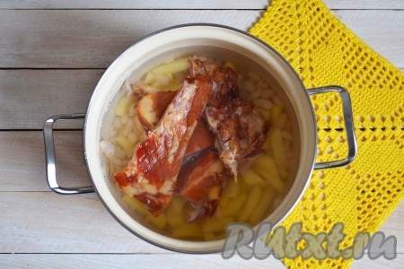 Копченые ребрышки разрезать небольшими порционными кусочками. Выложить в кастрюлю. 