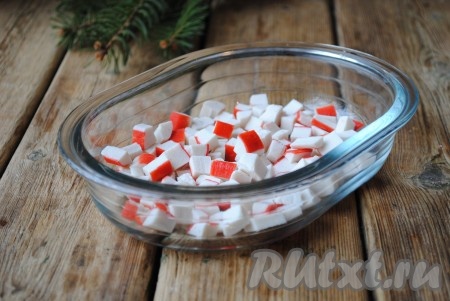 Крабовые палочки нарезать на небольшие кубики, выложить в салатницу первым слоем, сверху сделать сеточку из майонеза.