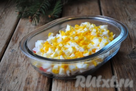 Сваренные яйца нарезать кубиками и выложить поверх крабовых палочек.&nbsp;