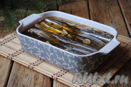 Чай соединить с растительным маслом, добавить чёрный перец горошком и лавровый лист. Залить рыбу чайной смесью, чтобы мойва была покрыта практически полностью. 